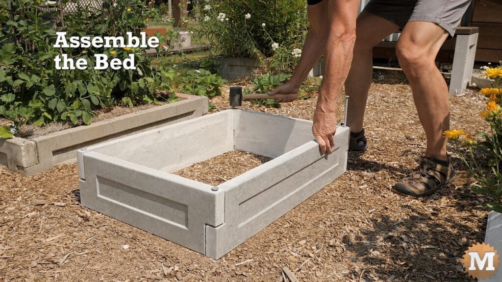 assembling a concrete raised garden bed in a garden