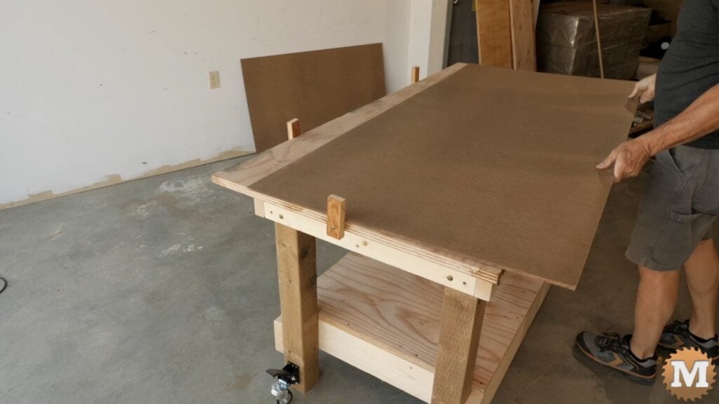 a man laying masonite over a plywood worktop