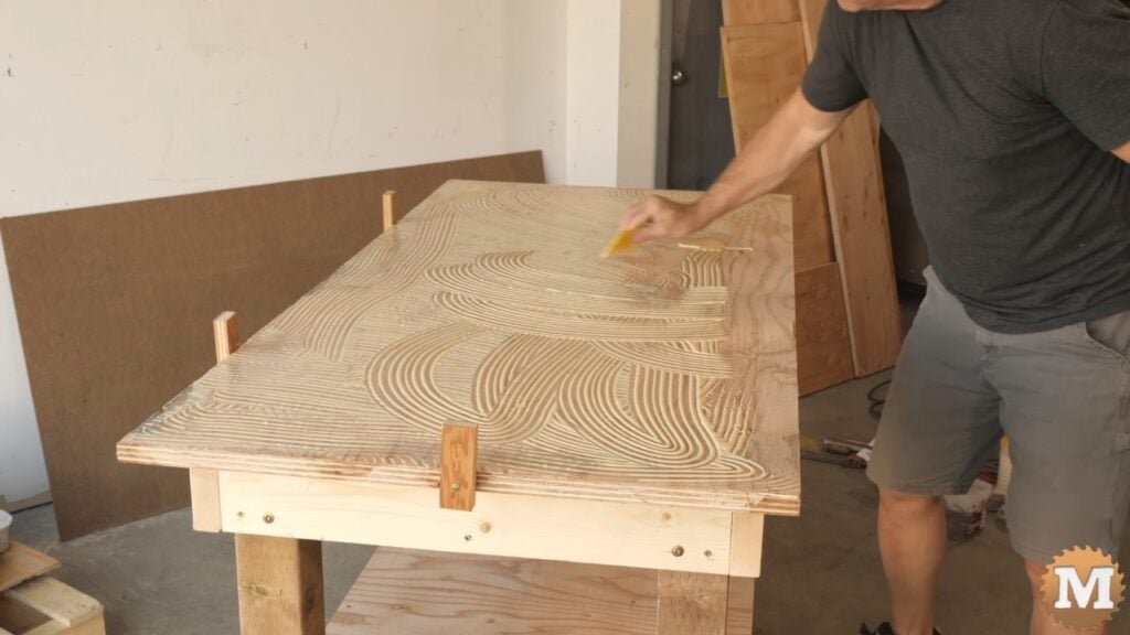 man applying glue to the top odf a workbench