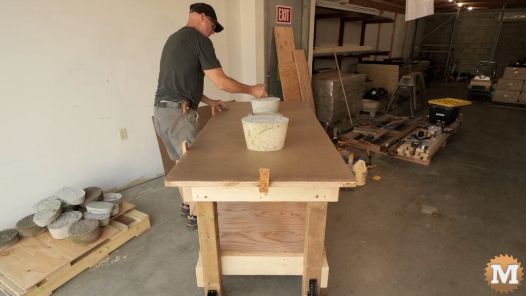 man placing concrete weights on the top of a workbench
