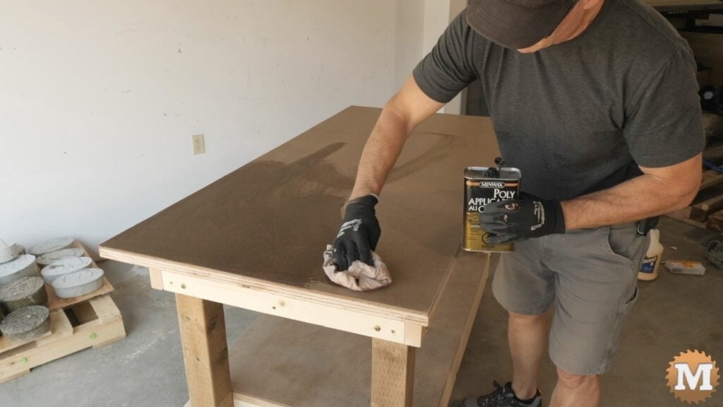 man applying finish to workbench with a rag